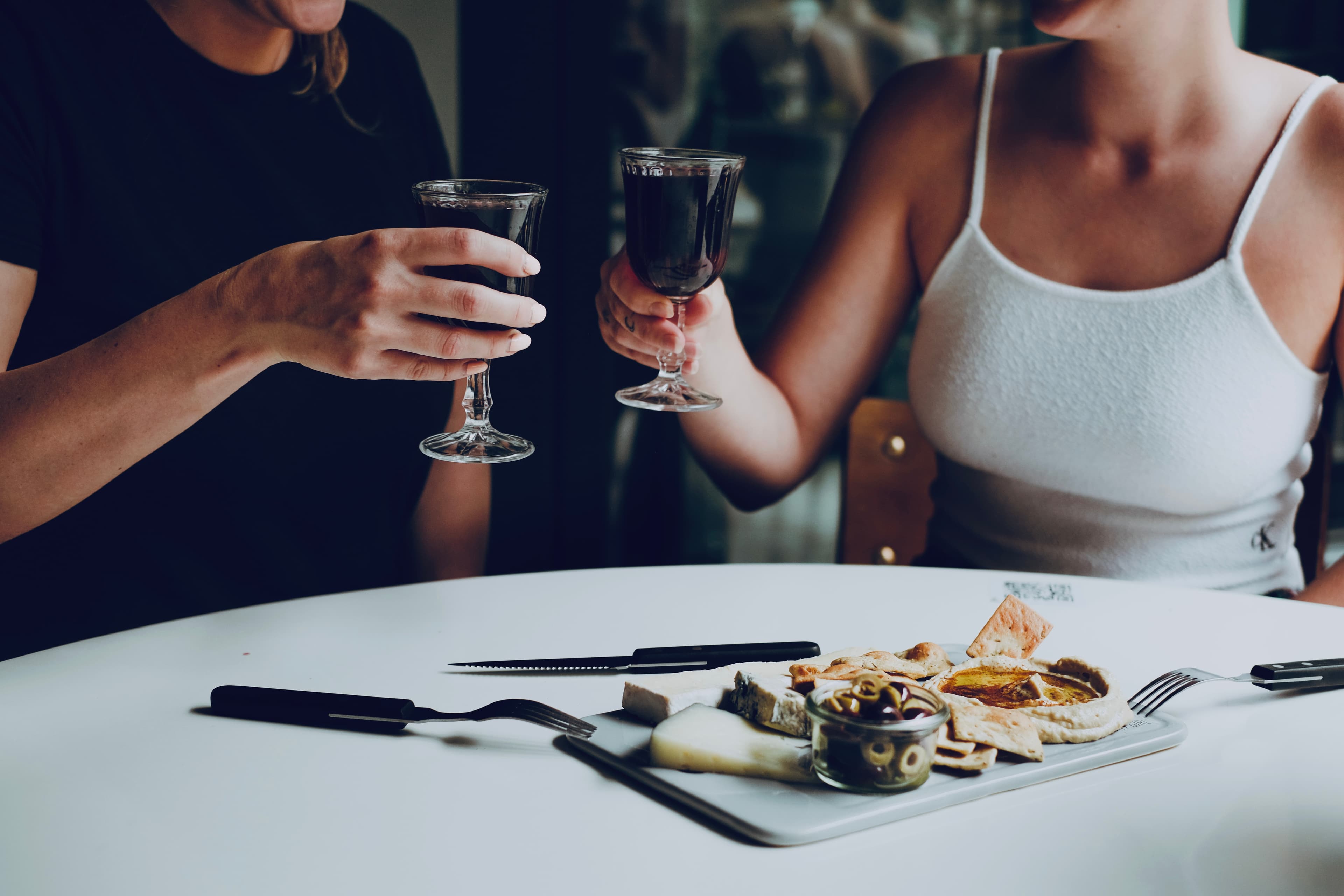 Two guests toasting over wine and small plates at a Factory Girl table